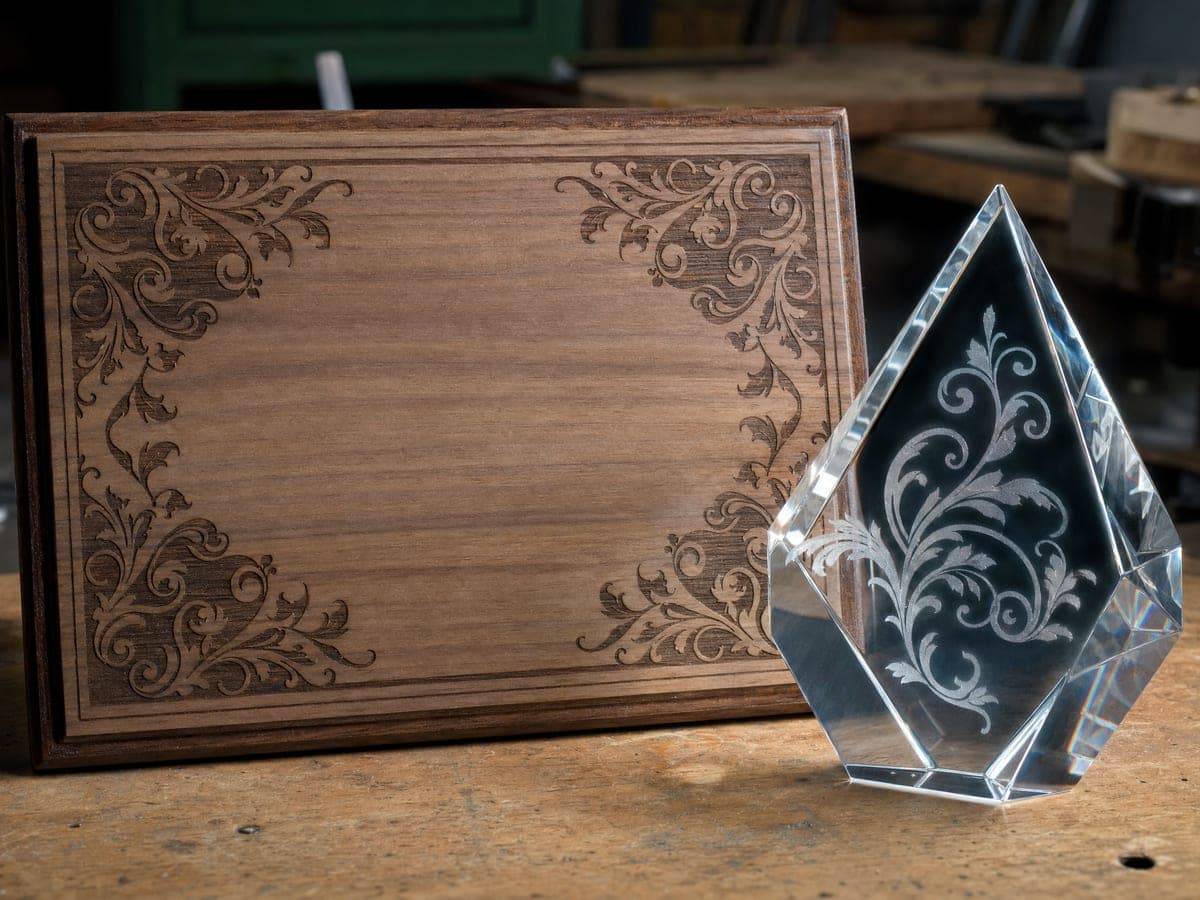 Laser-engraved wooden plaque and crystal award on a table